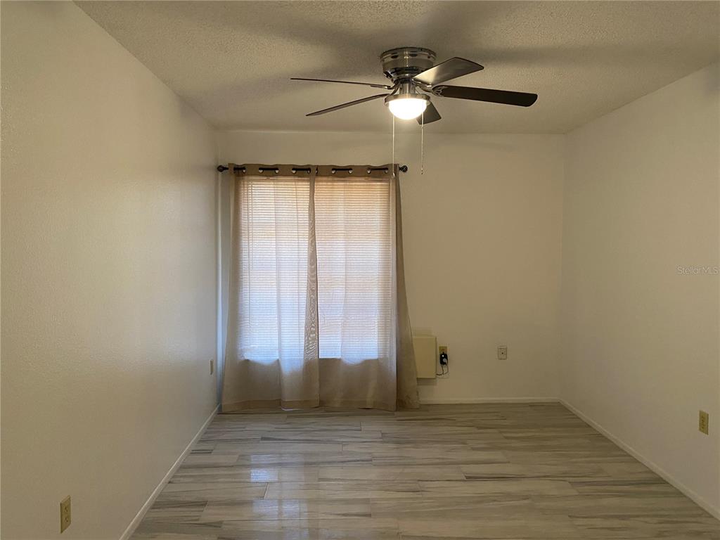 A room with light-colored tile flooring, white walls, a ceiling fan, and a window — 4377 TAHITIAN GARDENS CIRCLE UNIT G, HOLIDAY, FL