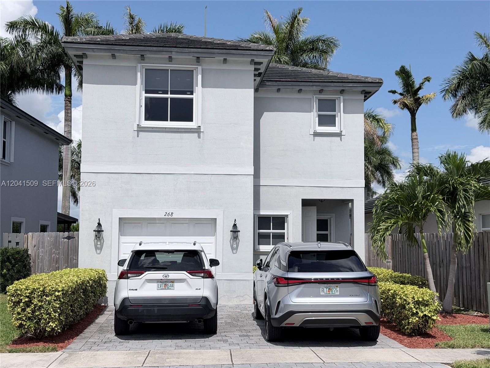 A two-story house with a white exterior, a garage, and two cars parked in the driveway — 268 SE 31st Ave, Homestead FL 33033, HOMESTEAD, FL