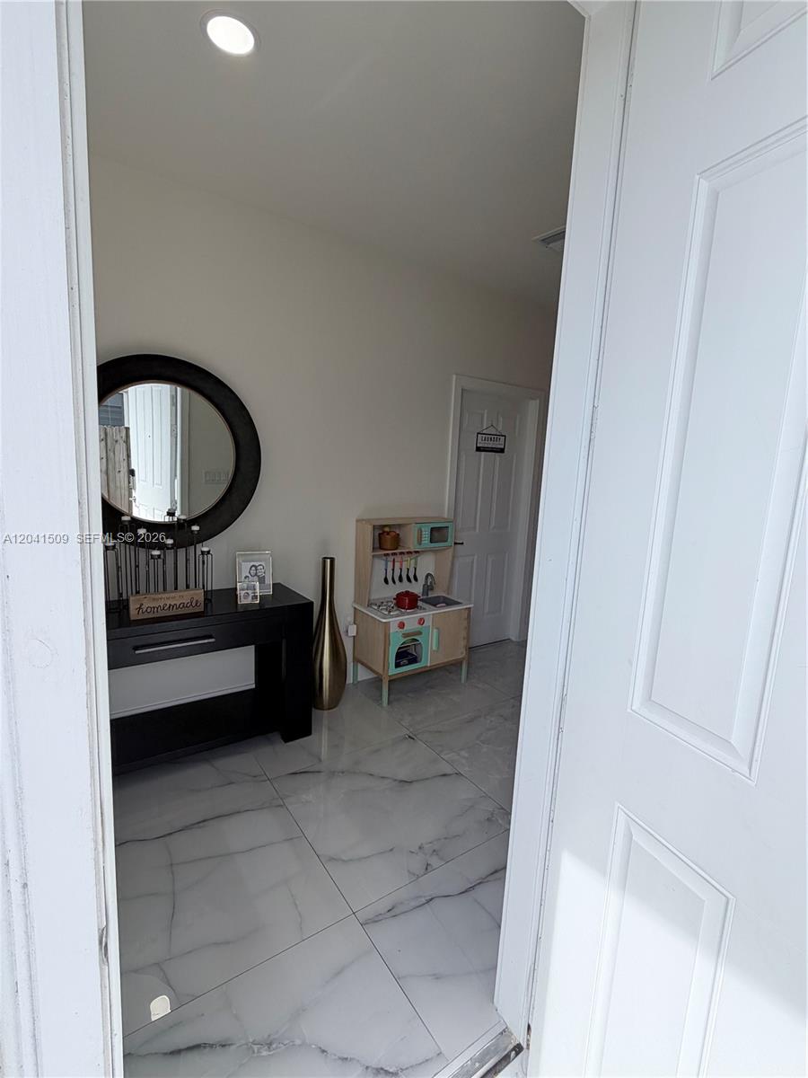 A tiled entryway features a black console table with a mirror and a toy kitchen — 268 SE 31st Ave, Homestead FL 33033, HOMESTEAD, FL