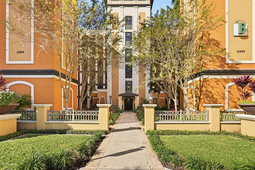 A sidewalk leads to the entrance of an orange multi-story apartment building — 12544 FLORIDAYS RESORT DRIVE UNIT 312B, ORLANDO, FL