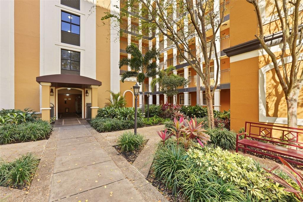 A paved walkway leads to a building entrance surrounded by landscaping and a red bench — 12544 FLORIDAYS RESORT DRIVE UNIT 312B, ORLANDO, FL