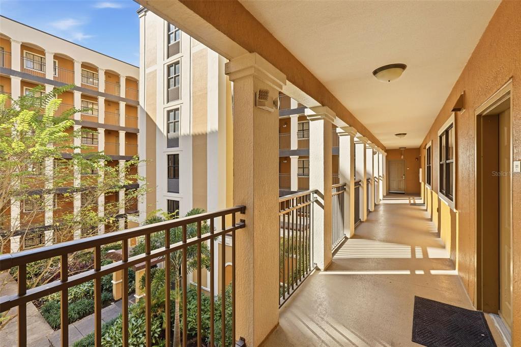An outdoor apartment hallway with a metal railing overlooking a courtyard with trees — 12544 FLORIDAYS RESORT DRIVE UNIT 312B, ORLANDO, FL