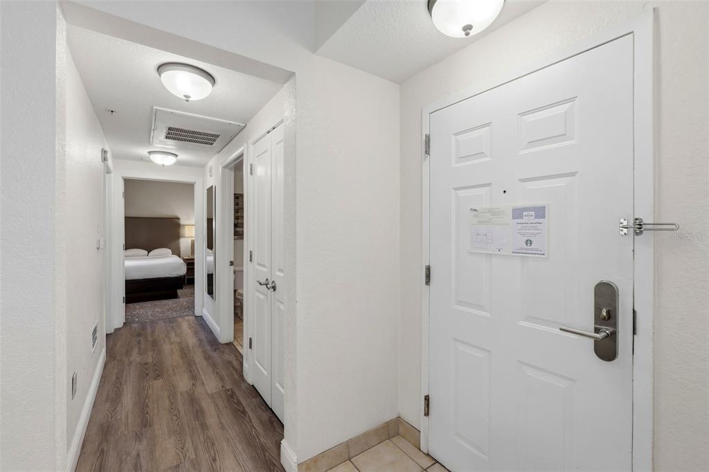 An entryway with a white door, wood-look flooring, and a view into a bedroom — 12544 FLORIDAYS RESORT DRIVE UNIT 312B, ORLANDO, FL