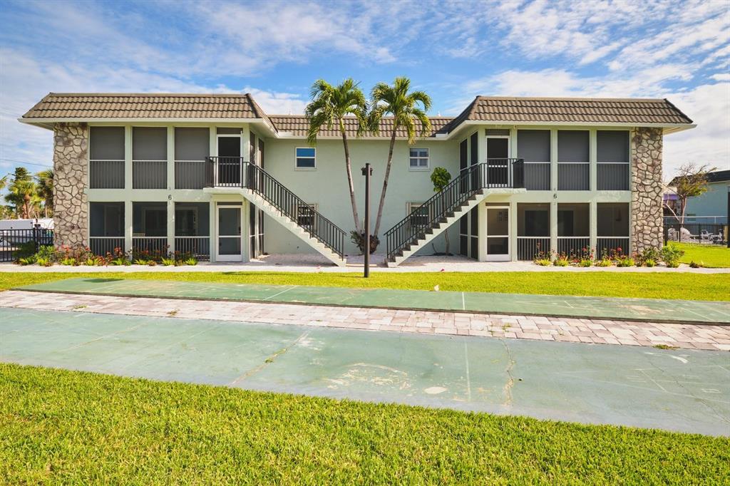 A two-story apartment building with screened balconies, exterior staircases, and a shuffleboard court in front — 3045 ESTERO BOULEVARD UNIT 6A, FORT MYERS BEACH, FL