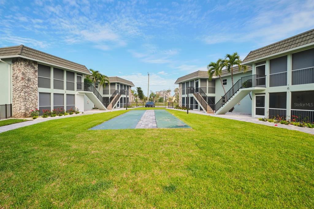 Exterior view of two-story apartment buildings with a central lawn and shuffleboard court — 3045 ESTERO BOULEVARD UNIT 6A, FORT MYERS BEACH, FL
