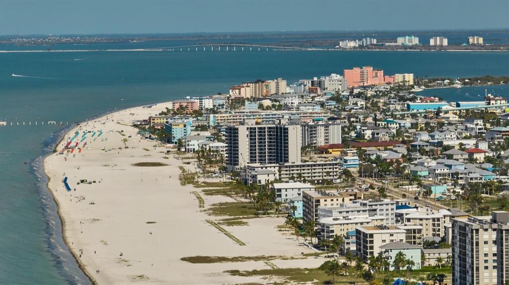 An aerial view shows a sandy beach lined with high-rise buildings and coastal residential properties — 3045 ESTERO BOULEVARD UNIT 6A, FORT MYERS BEACH, FL