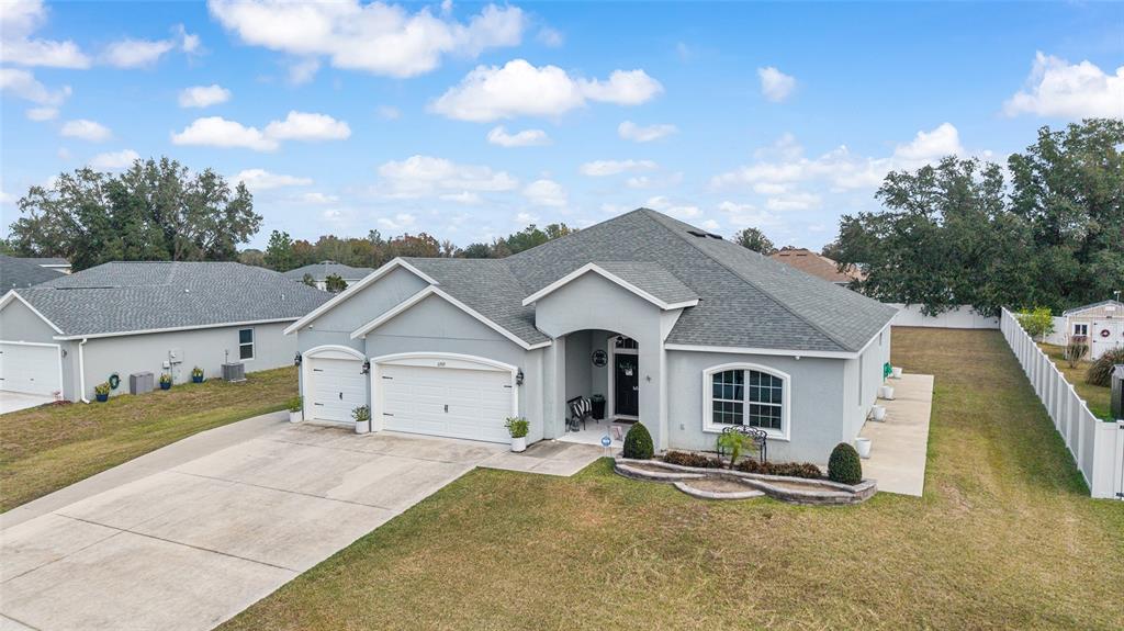 An exterior view of a single-story gray house with a multi-car garage and lawn — 11769 SW 60TH COURT, OCALA, FL