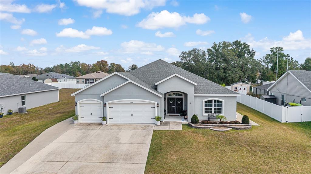 A single-story house with a gray stucco exterior, a three-car garage, and a concrete driveway — 11769 SW 60TH COURT, OCALA, FL