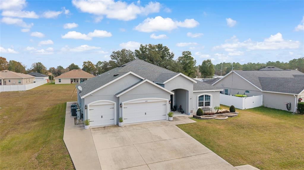 An exterior view of a single-story suburban house with a three-car garage and driveway — 11769 SW 60TH COURT, OCALA, FL