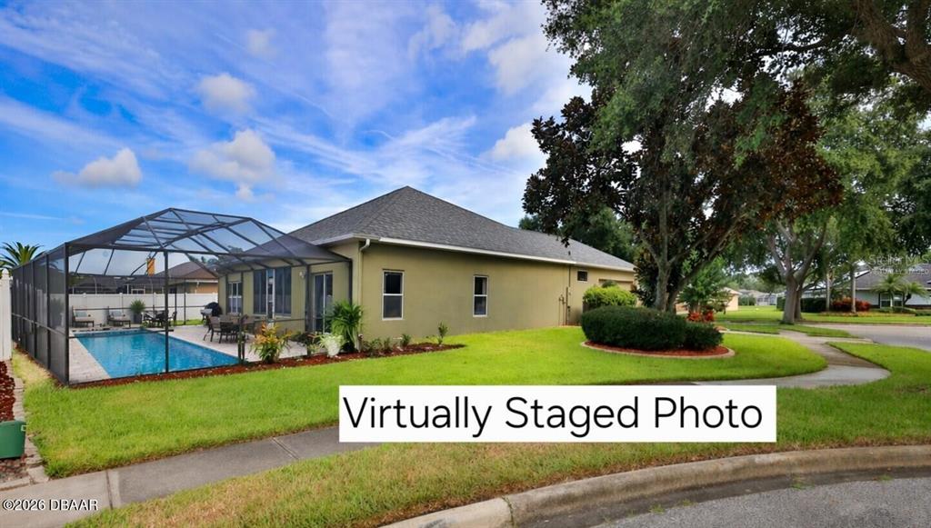 The exterior of a house features a screened-in swimming pool and a grassy yard — 4269 MAYFAIR LANE, PORT ORANGE, FL
