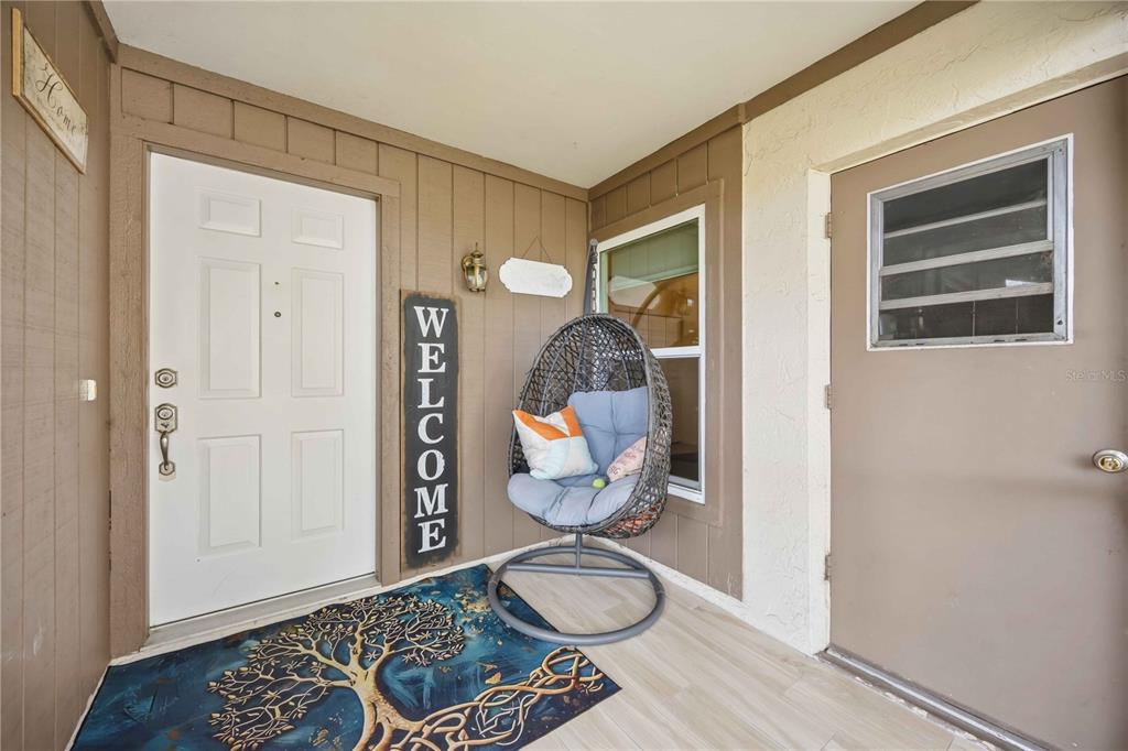 A covered porch features a white front door, a side door, and a hanging egg chair — 266 OAK HILL DRIVE UNIT 34, SARASOTA, FL
