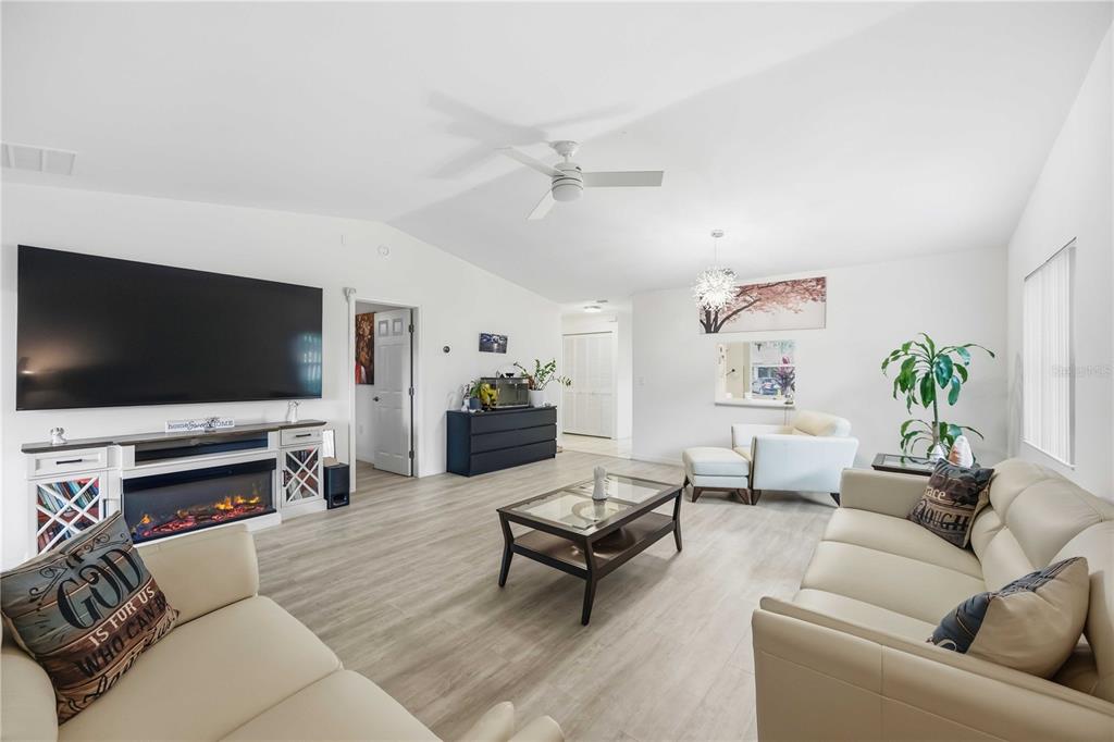 A living room features light wood-look flooring, a large television, and a fireplace console — 266 OAK HILL DRIVE UNIT 34, SARASOTA, FL