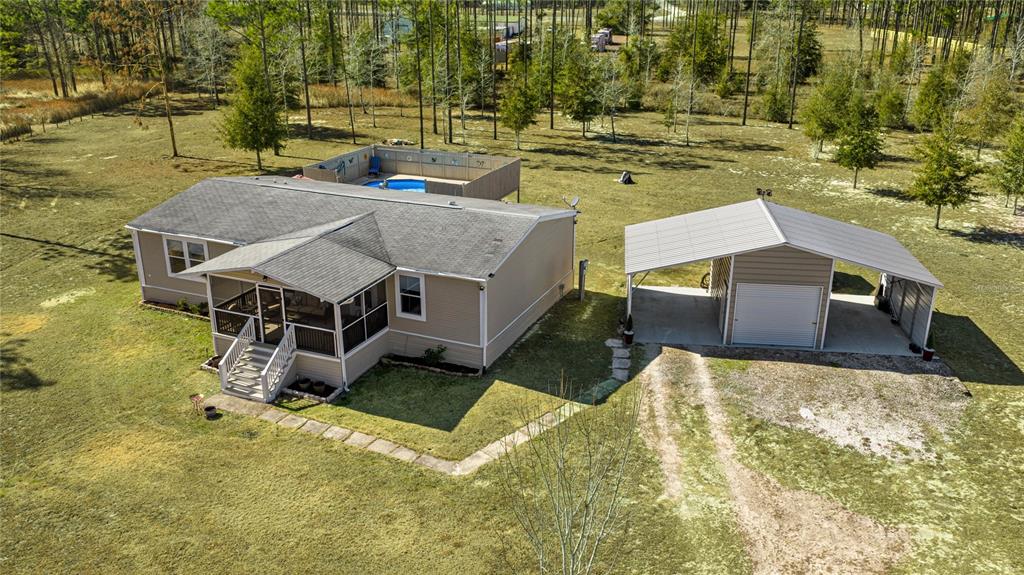 An aerial view shows a single-story house with a screened porch, pool, and detached carport — 5130 SE 137TH AVENUE, MORRISTON, FL
