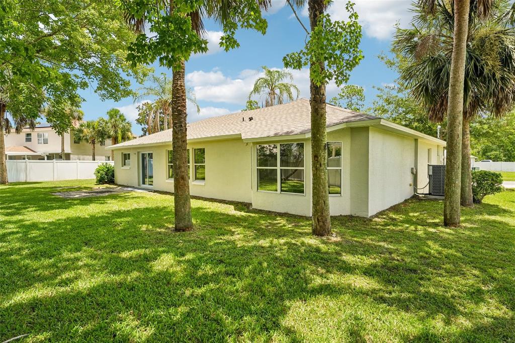 The exterior of a light-colored house with a grassy backyard and several palm trees — 19 EMERSON DRIVE, PALM COAST, FL