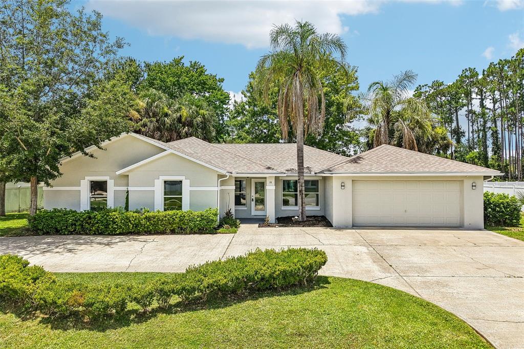 A single-story house with a beige exterior, a two-car garage, and a palm tree — 19 EMERSON DRIVE, PALM COAST, FL