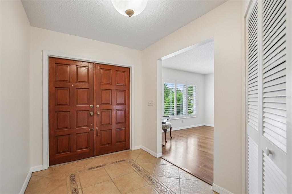 An entryway features double wood doors, tiled flooring, and a view into a living area — 4541 CHARING CROSS ROAD, SARASOTA, FL