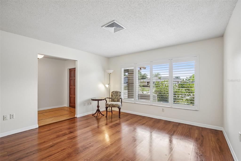 A living room features wood-look flooring, white walls, plantation shutters, and a small sitting area — 4541 CHARING CROSS ROAD, SARASOTA, FL