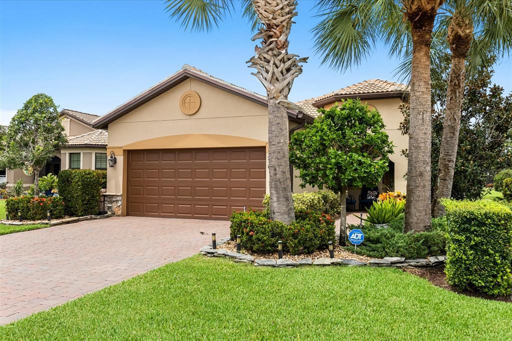 A tan house with a brown garage door, palm trees, and a landscaped front yard — 218 SE LONGVIEW DRIVE, PORT ST LUCIE, FL