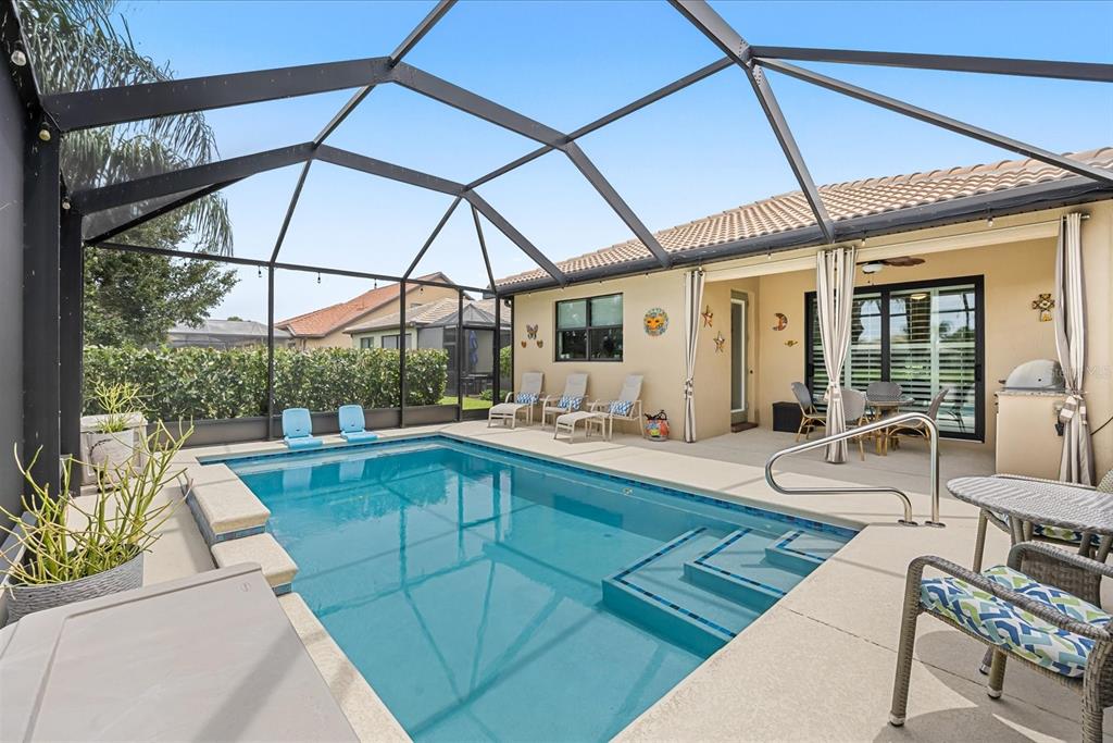 A screened-in patio features a rectangular swimming pool with steps and surrounding lounge furniture — 218 SE LONGVIEW DRIVE, PORT ST LUCIE, FL