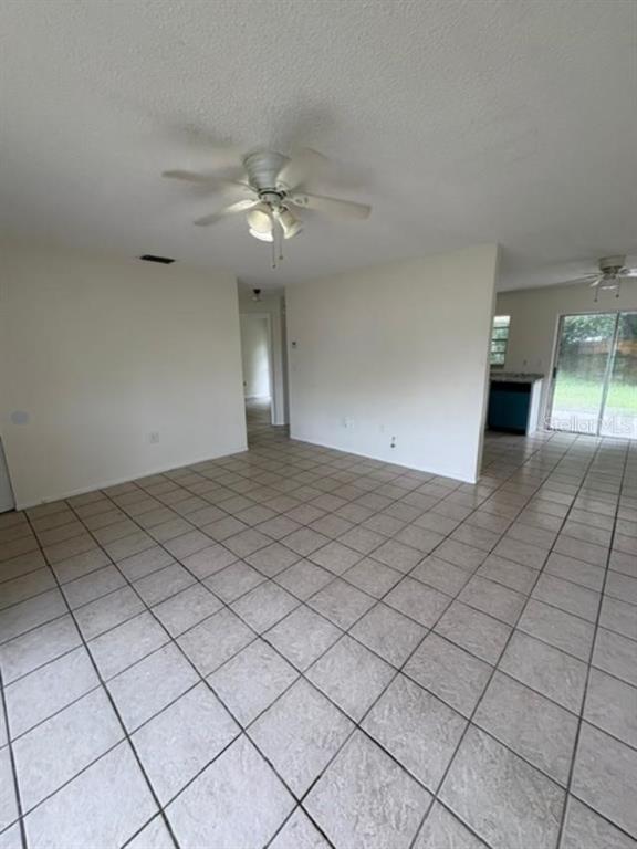 An open-concept living area features light-colored tile flooring, white walls, and two ceiling fans — 7238 EXEMPLAR DRIVE, NEW PORT RICHEY, FL