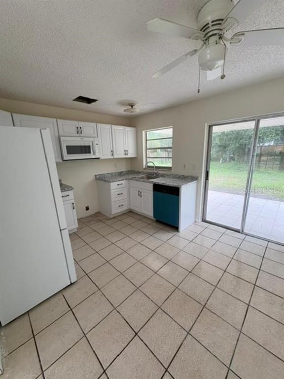 A kitchen with white cabinets, granite-look countertops, a blue dishwasher, and tile flooring — 7238 EXEMPLAR DRIVE, NEW PORT RICHEY, FL