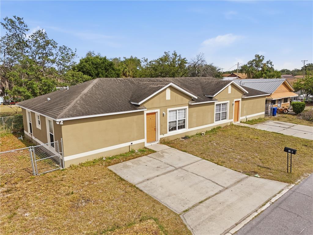 An exterior view of a tan, single-story house with a concrete driveway and fenced yard — 1830 2ND STREET NW UNIT A, WINTER HAVEN, FL