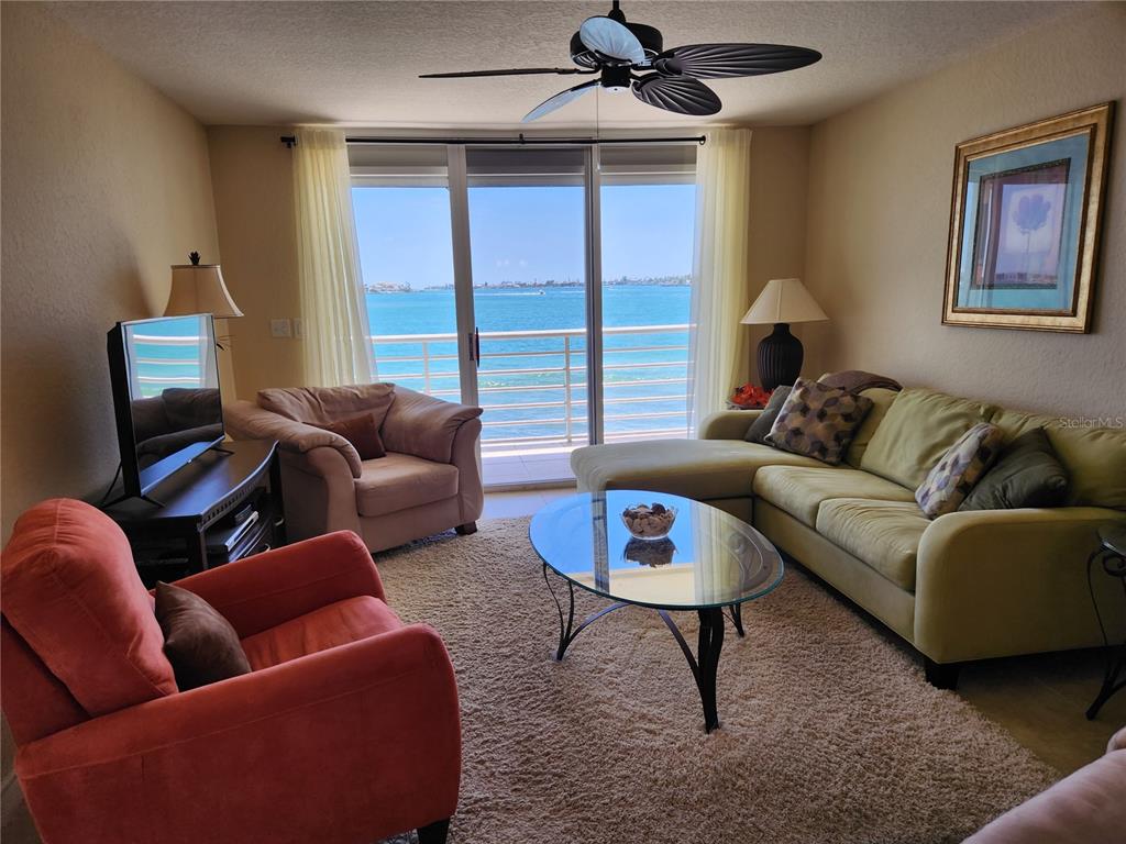 A living room features a sectional sofa, armchairs, a glass coffee table, and a balcony view — 6105 BAHIA DEL MAR CIRCLE UNIT 283, ST PETERSBURG, FL