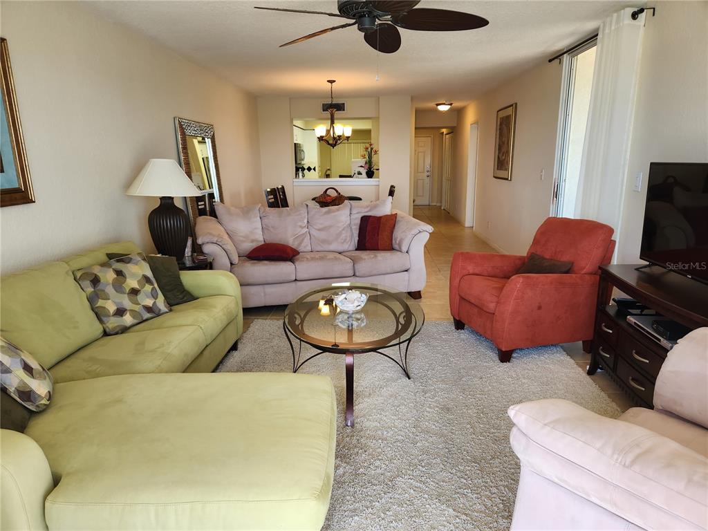 A living room features a light green sectional, a beige sofa, and an orange armchair — 6105 BAHIA DEL MAR CIRCLE UNIT 283, ST PETERSBURG, FL