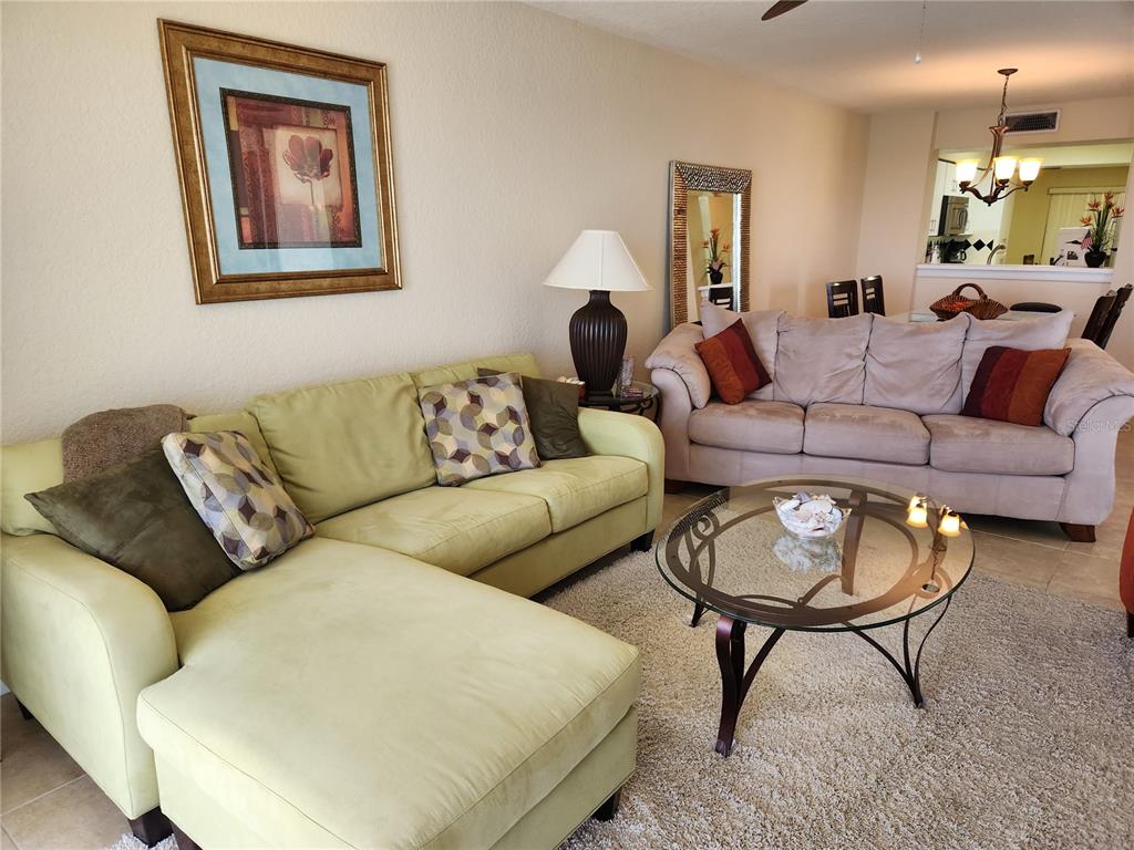 A living room features a light green sectional sofa, a beige sofa, and a glass coffee table — 6105 BAHIA DEL MAR CIRCLE UNIT 283, ST PETERSBURG, FL