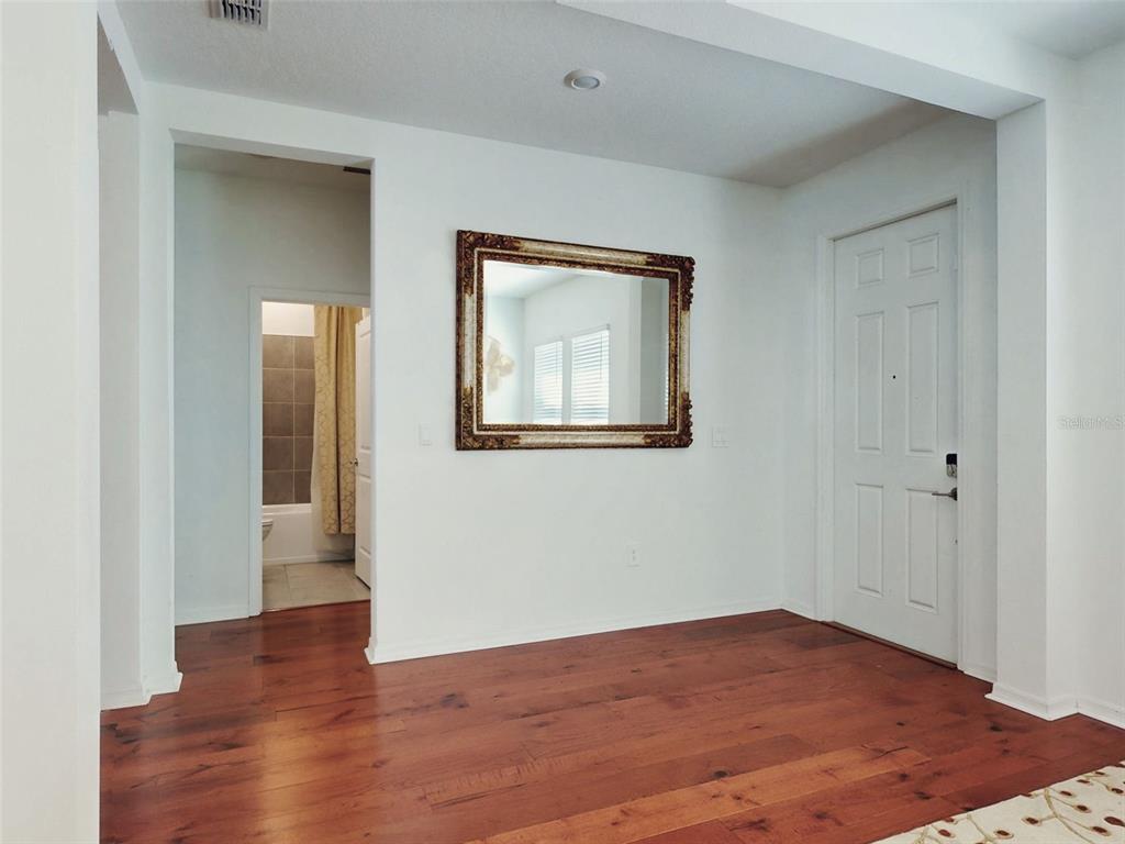 An entryway features hardwood floors, a white door, and a large mirror on the wall — 6084 CLAYSTONE WAY, MOUNT DORA, FL