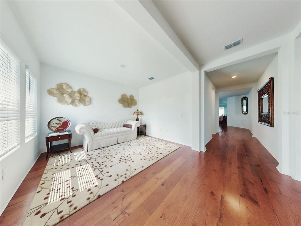 A living area features hardwood floors, a white tufted sofa, and a patterned area rug — 6084 CLAYSTONE WAY, MOUNT DORA, FL