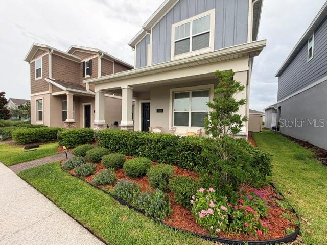 A two-story house with a front porch and landscaped garden sits beside a neighboring home — 1704 FRIENDSHIP ROW, KISSIMMEE, FL
