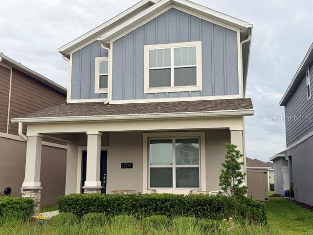 A two-story house with blue vertical siding, a front porch, and a manicured hedge — 1704 FRIENDSHIP ROW, KISSIMMEE, FL