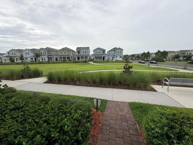 A paved walkway leads toward a grassy park area surrounded by suburban houses — 1704 FRIENDSHIP ROW, KISSIMMEE, FL