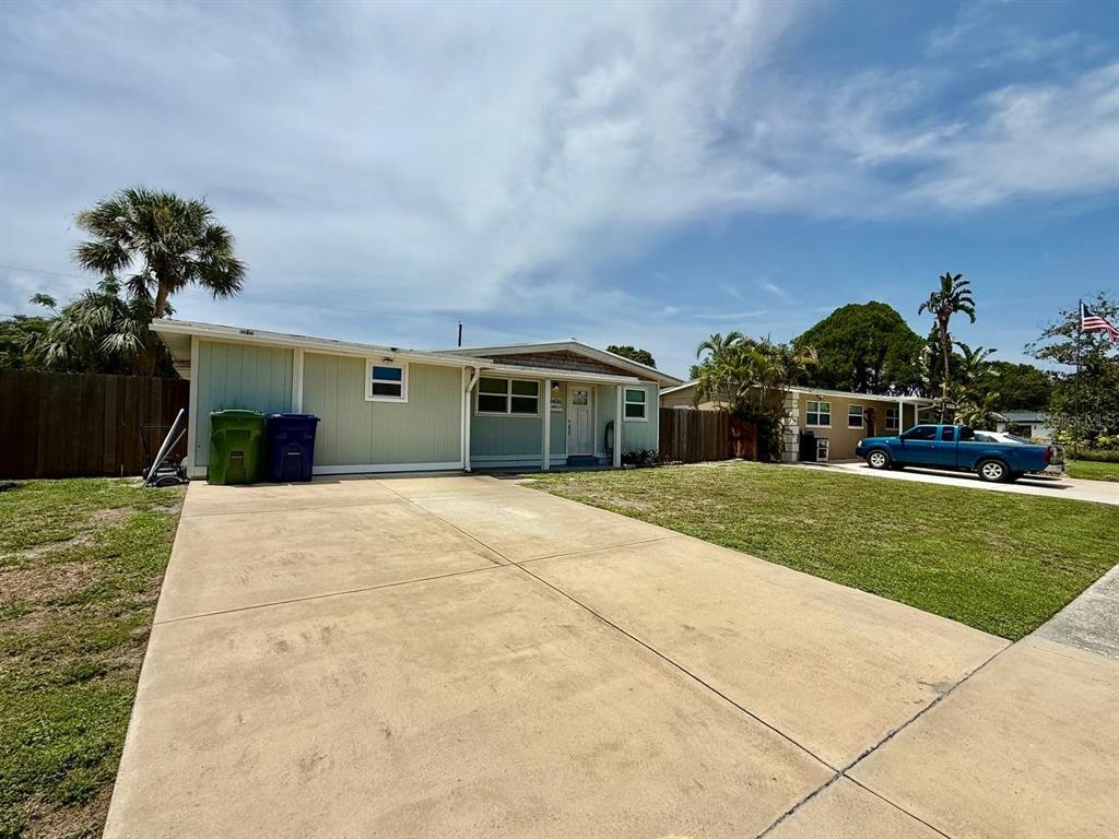 A single-story house with light green siding and a concrete driveway under a blue sky — 4406 W TRILBY AVENUE, TAMPA, FL