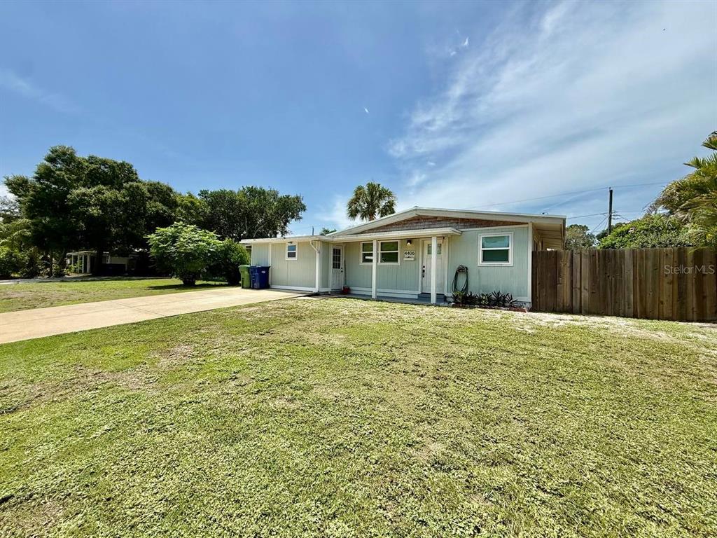 A light green single-story house with a concrete driveway and a wooden privacy fence — 4406 W TRILBY AVENUE, TAMPA, FL