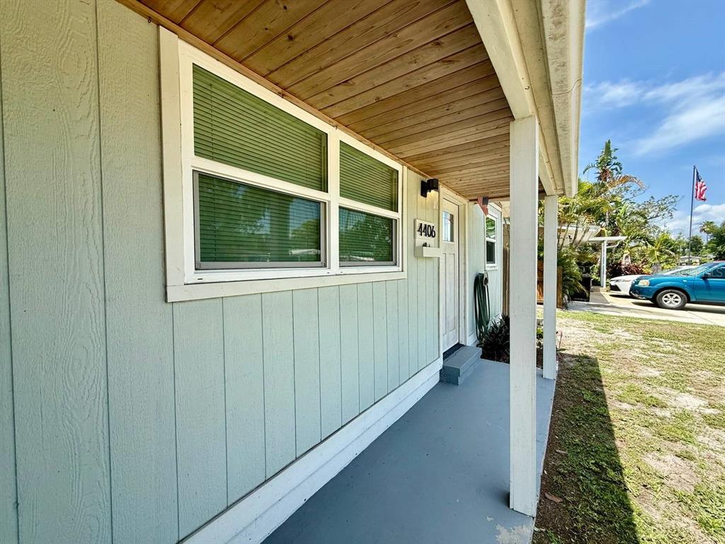 A light green house exterior features a covered porch, wood-paneled ceiling, and a white door — 4406 W TRILBY AVENUE, TAMPA, FL