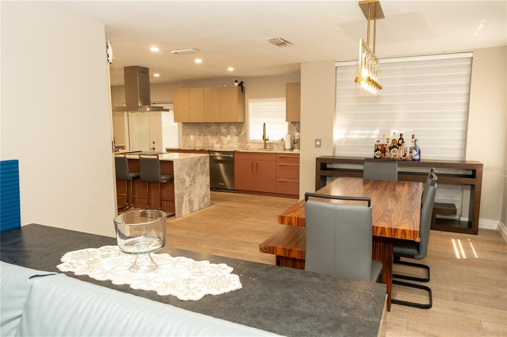 An open-concept kitchen and dining area featuring wood-look flooring, a marble island, and modern cabinetry — 10740 NW 12TH MANOR, PLANTATION, FL