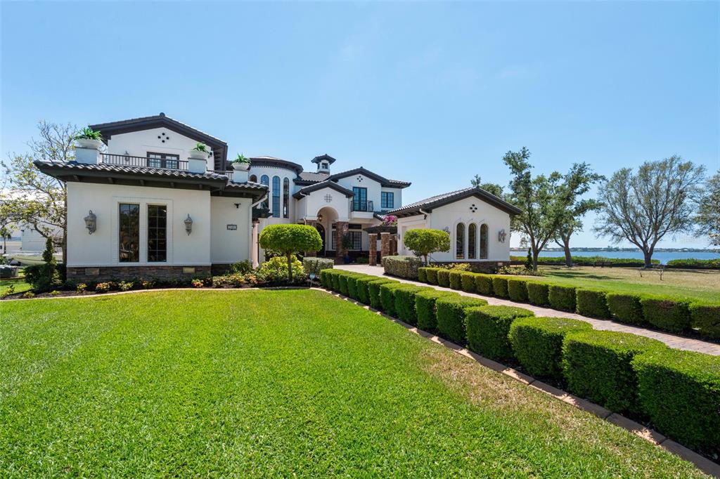A large, two-story Mediterranean-style house with a manicured lawn and a long hedge-lined walkway — 2107 4TH STREET COURT W, PALMETTO, FL