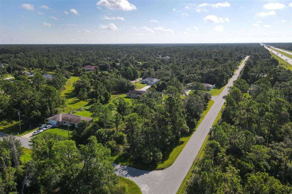 An aerial view shows a suburban street lined with houses surrounded by dense wooded areas — Lot # 19 RENTSCHER AVENUE, NORTH PORT, FL