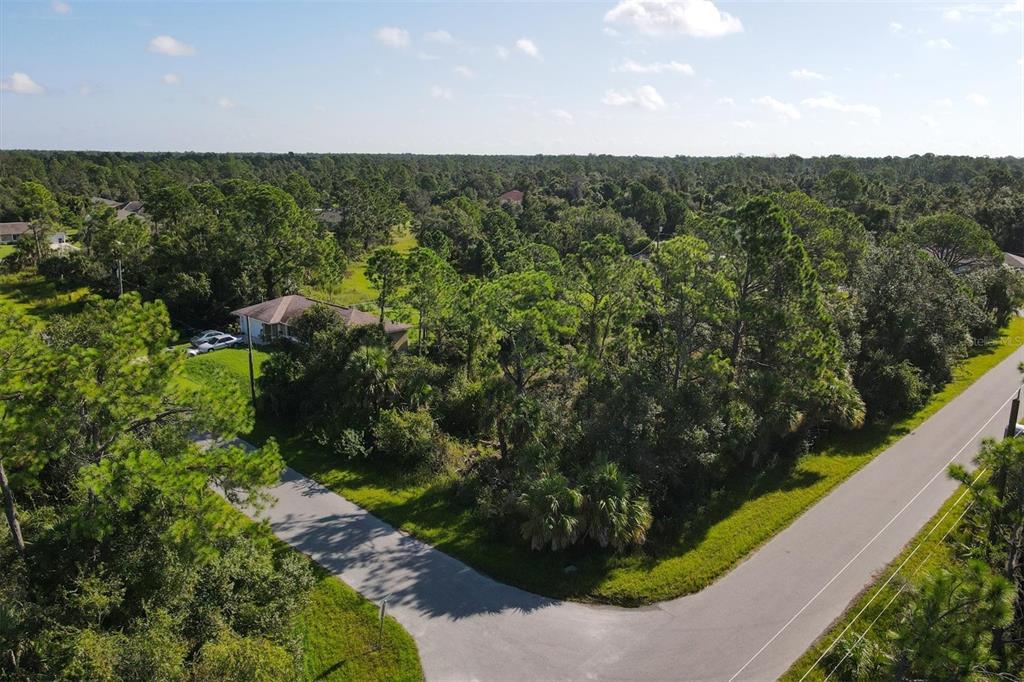 An aerial view shows a house surrounded by dense trees at a road intersection — Lot # 19 RENTSCHER AVENUE, NORTH PORT, FL