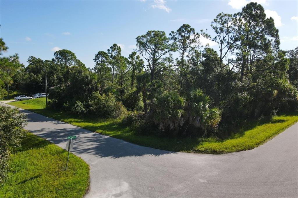 An aerial view shows a corner lot with dense trees and vegetation at a road intersection — Lot # 19 RENTSCHER AVENUE, NORTH PORT, FL