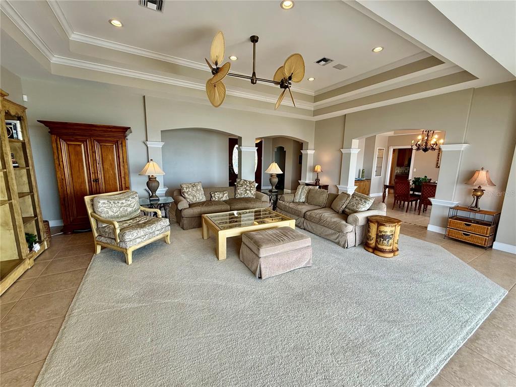 A living room with a tray ceiling, beige carpet, and neutral-toned furniture — 376 W ROYAL FLAMINGO DRIVE, SARASOTA, FL