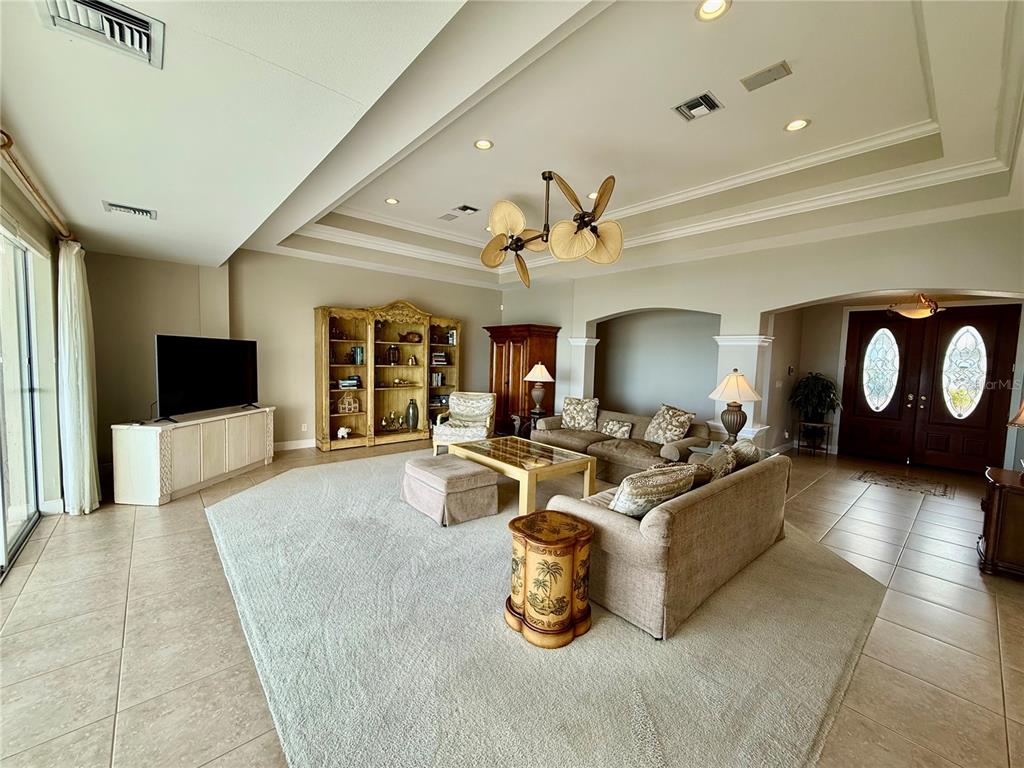 A spacious living room features a tray ceiling, tile flooring, and a large area rug — 376 W ROYAL FLAMINGO DRIVE, SARASOTA, FL