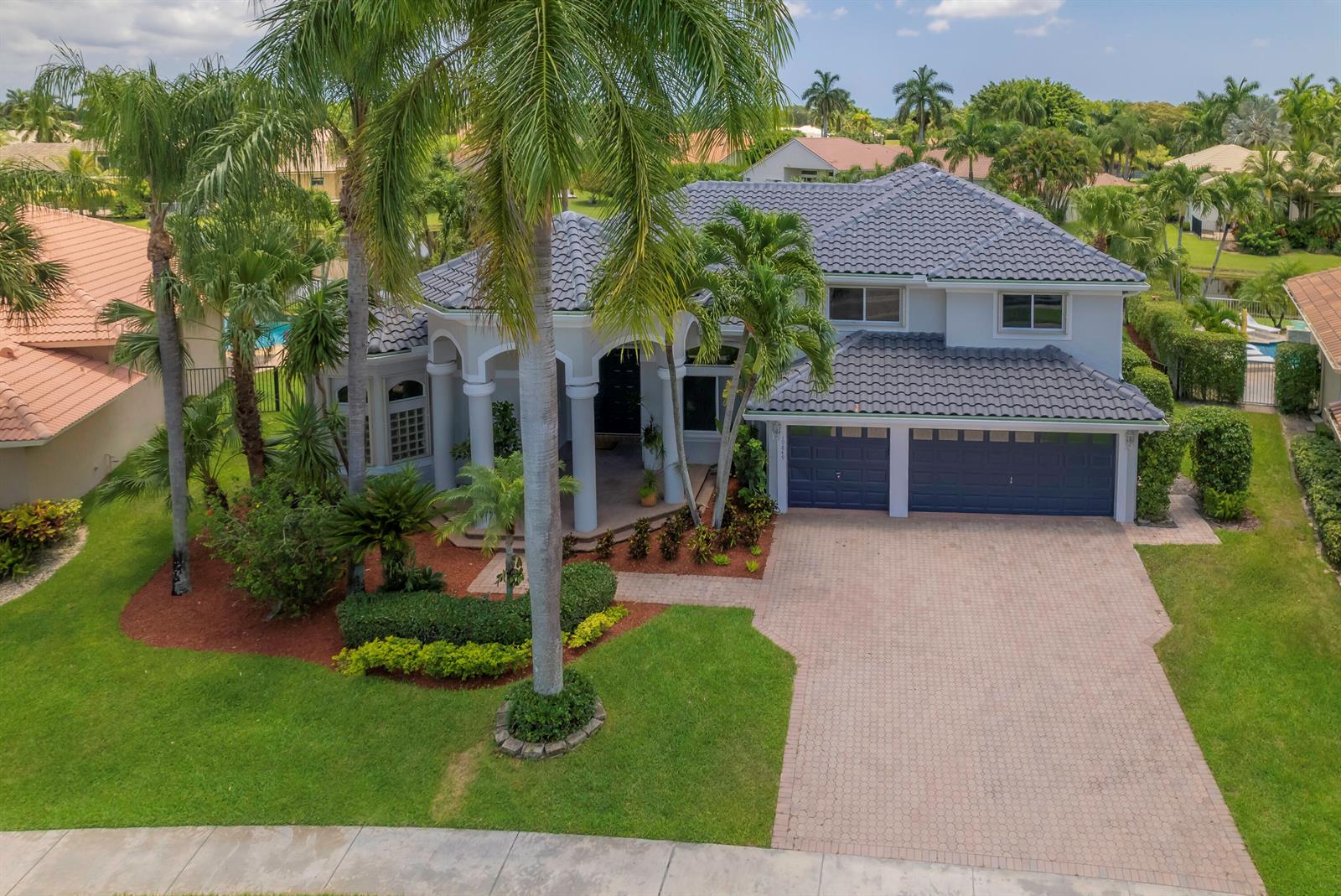 An aerial view of a two-story house with a tiled roof, palm trees, and driveway — 10849 Bal Harbor Drive, Boca Raton FL 33498, BOCA RATON, FL