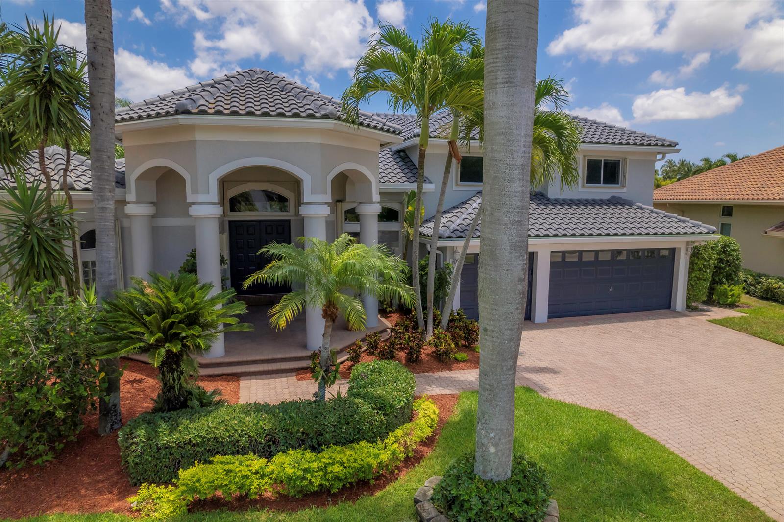 A two-story house with a gray tile roof, arched entryway, and a paved driveway — 10849 Bal Harbor Drive, Boca Raton FL 33498, BOCA RATON, FL