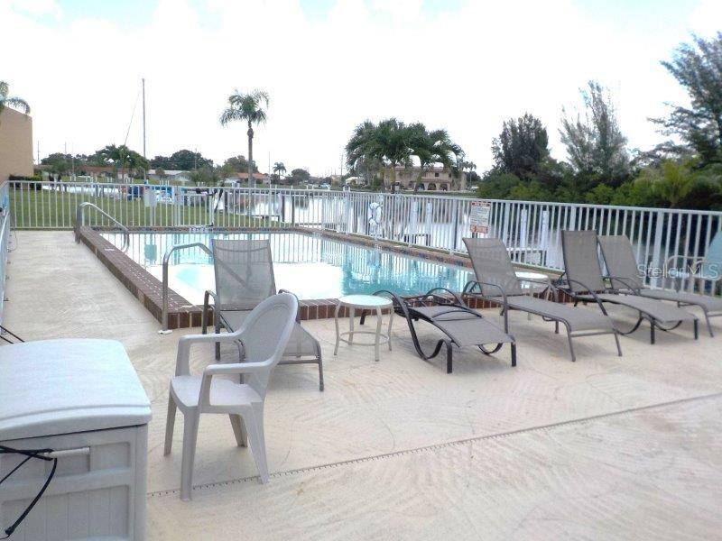 A swimming pool with lounge chairs on a concrete deck enclosed by a white fence — 1354 ROCK DOVE COURT UNIT A203, PUNTA GORDA, FL