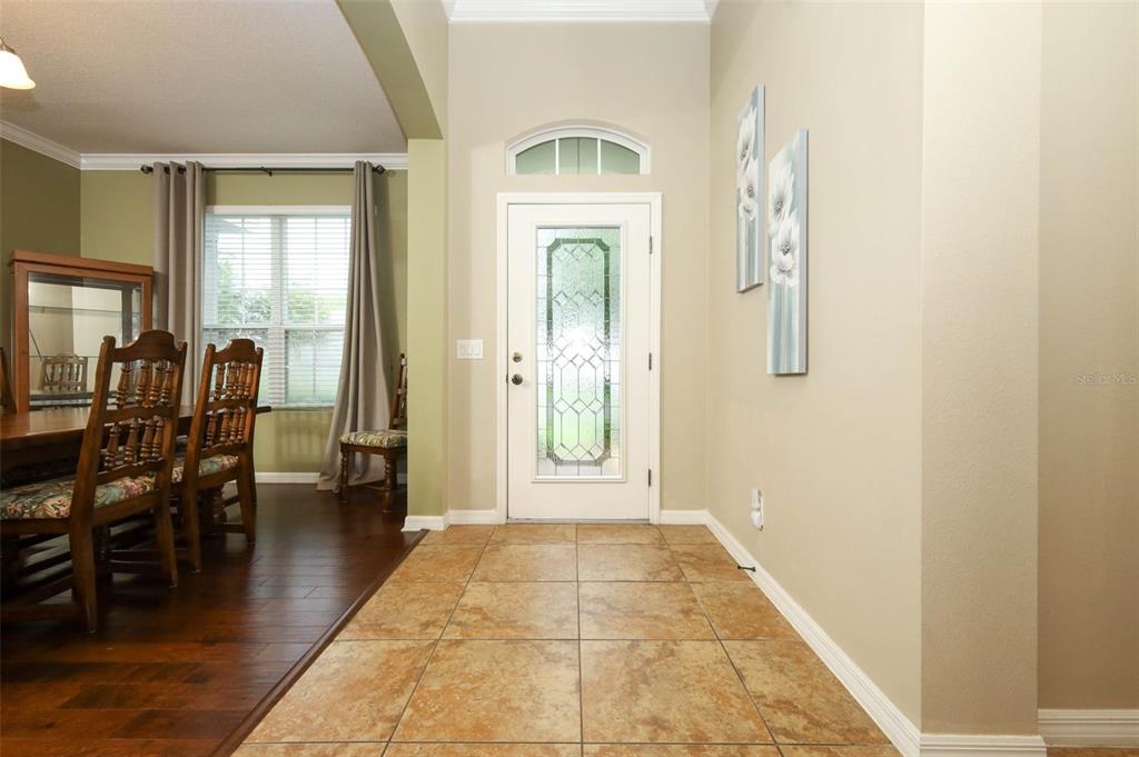 An entryway features a white front door with a glass insert and tan tile flooring — 1661 BLUE GRASS BOULEVARD, DELAND, FL