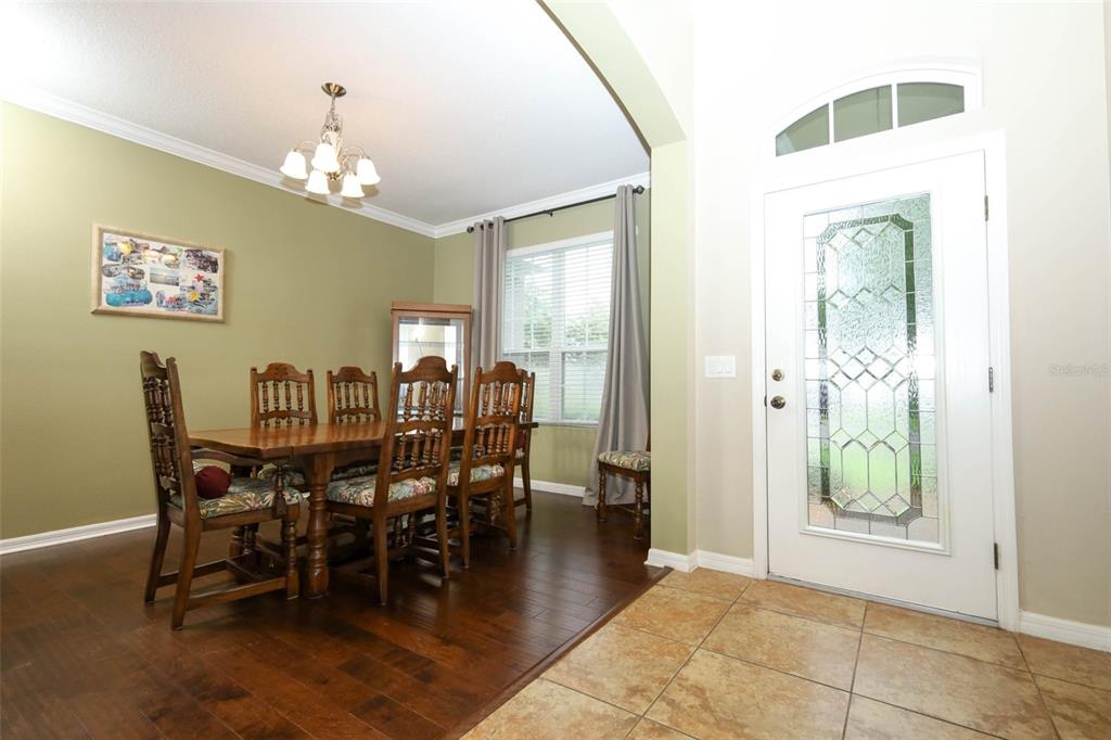 A dining room with hardwood floors and a tiled entryway featuring a glass-paneled front door — 1661 BLUE GRASS BOULEVARD, DELAND, FL