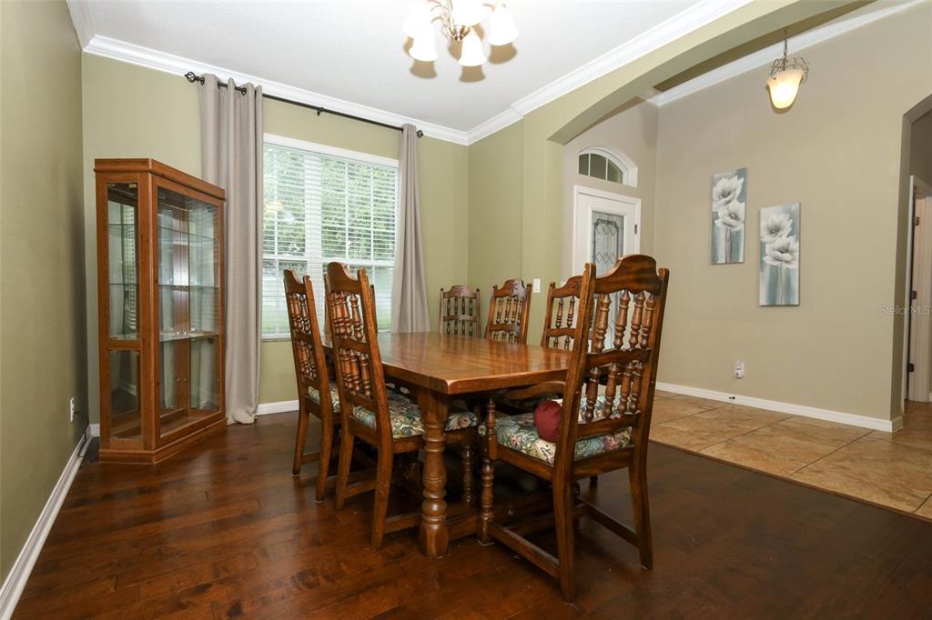 A dining room features a wooden table and chairs, a curio cabinet, and hardwood flooring — 1661 BLUE GRASS BOULEVARD, DELAND, FL